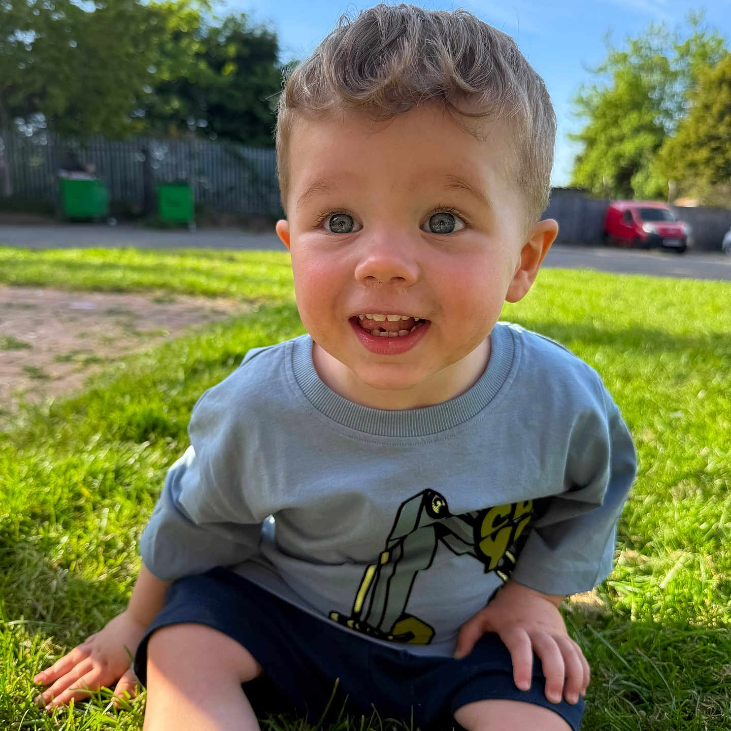 Hunter is registered to the contest to win money with this photo: baby, car, clothing, face, grass, head, lawn, nature, outdoors, pants, park, person, photography, plant, portrait, shorts, sitting, t_shirt, transportation, vehicle