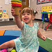 Mikenna joined the competition — help win amazing prizes! toddler, child, toy, ice_cream_cone, playroom, classroom, colorful, dress, smiling, sitting, floor, plastic_toys, indoor, young_child, happy, play, educational, furniture, carpet, cute
