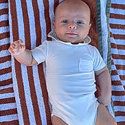 Livio participe au concours pour gagner de l'argent avec cette photo : baby, infant, towel, striped_towel, white_onesie, clothing, blue_eyes, cute, laying_down, portrait, child, skin, hand, face, head, soft_light, relaxed, casual, summer, outdoor