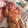 newborn, baby, infant, child, portrait, face, hat, beanie, onesie, bear, clothing, blanket, bed, bedding, indoor, lying_down, hand, caregiver, cozy, cute