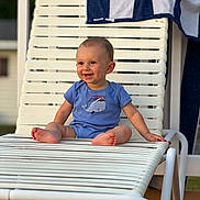 Colton joined the competition — help win amazing prizes! baby, child, smiling, blue_onesie, lounge_chair, white_chair, towel, striped_towel, outdoor, sunlight, happy, cute, infant, sitting, barefoot, portrait, summer, deck, wood_floor, relaxation