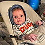 baby, baby_rocker, blanket, casual, child, comfort, curious_expression, electronics, face, furniture, hands, headwear, hoodie, indoor, infant, person, seated, striped_clothing, television, young_child