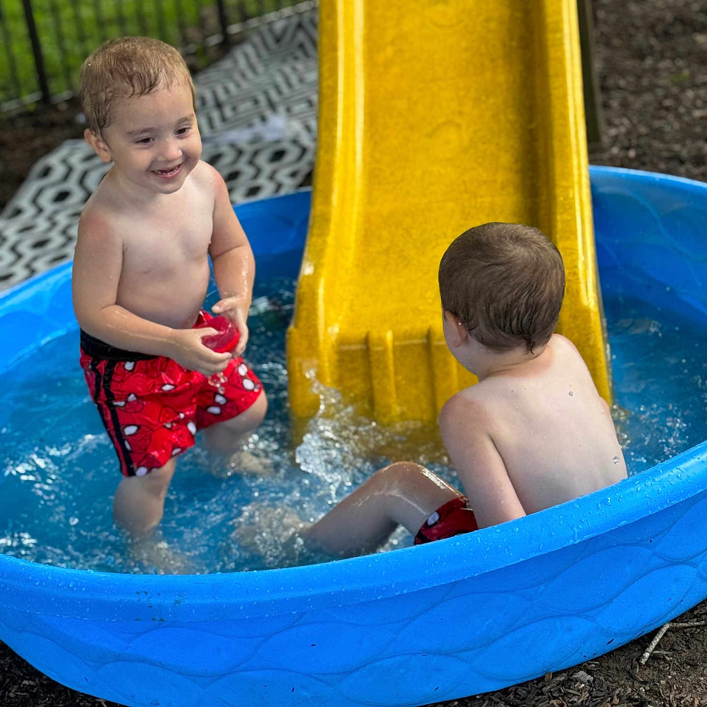 Mylin joined the competition — help win amazing prizes! child, pool, water, slide, outdoor, play, summer, fun, splash, kids, swimwear, red_shorts, blue_pool, yellow_slide, smile, wet_hair, backyard, fence, grass, happy