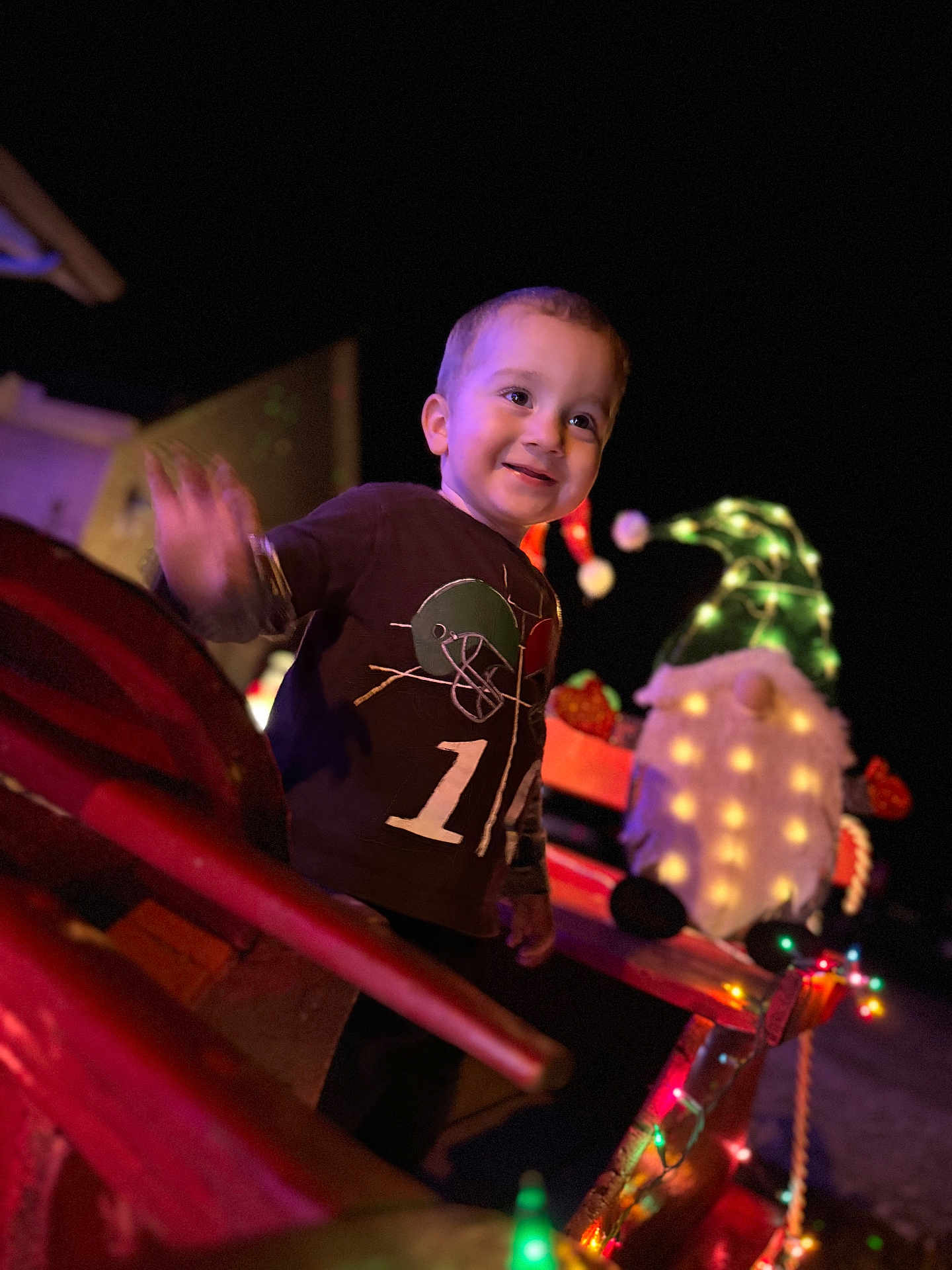 Mylin joined the competition — help win amazing prizes! child, toddler, smiling, waving, holiday, gnome, lights, night, festive, decoration, outdoor, clothing, happy, cute, person, toy, illumination, celebration, colorful, blurred_background