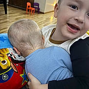 Dallas is registered to the contest to win money with this photo: toddler, child, hug, smile, indoor, blanket, paw_patrol, floor, wooden_floor, furniture, chair, playroom, happy, cuddle, person, clothing, head, face, arm, cute