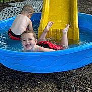 Dallas joined the competition — help win amazing prizes! backyard, boy, child, fence, fun, grass, happy, outdoor, play, pool, puddle, red_swim_trunks, slide, smile, splash, summer, sunlight, toddler, water, wet
