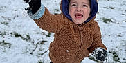 Dallas is registered to the contest to win money with this photo: brown, child, clothing, cold, doghouse, fun, gloves, grass, happy, hoodie, nature, outdoor, person, playful, smiling, snow, snowball, toddler, winter, yard