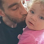 Youssef a rejoint le concours — aidez-le/la à gagner de superbes lots ! adult, affection, baby, beard, blue_eyes, child, close_up, cuddle, curly_hair, facial_expression, family, hand, holding, indoor, kiss, male, parent, pink_clothing, portrait, toddler