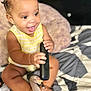 Germani is registered to the contest to win money with this photo: baby, bed, blanket, braided_hair, child, clothing, cute, feet, hands, happy, indoor, infant, pacifier, patterned_bedspread, plush_toy, remote_control, sitting, skin, smiling, toy