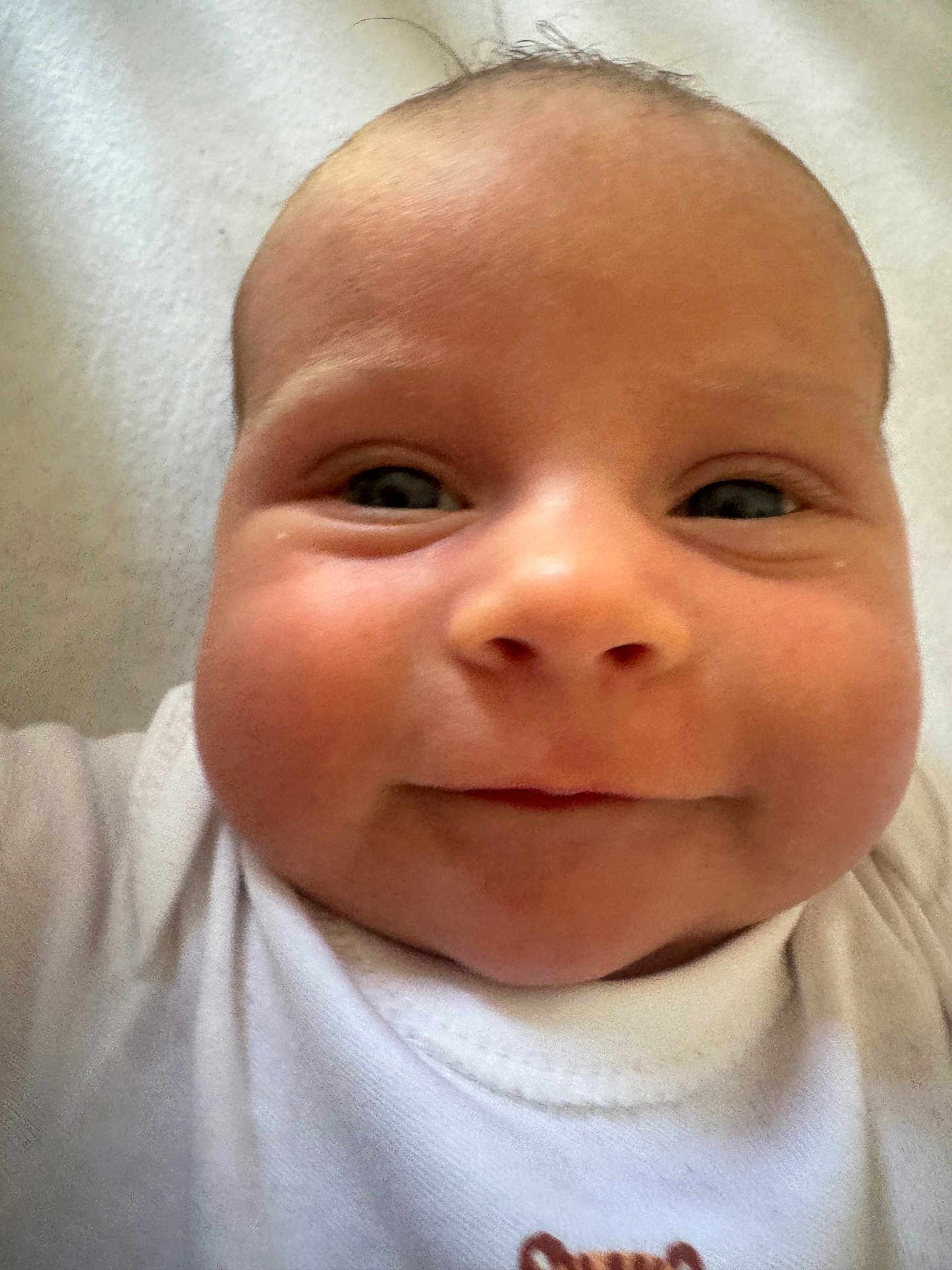 Kristofer is registered to the contest to win money with this photo: baby, close_up, face, smile, infant, white_clothing, chubby_cheeks, portrait, cute, young_child, skin, eyes, head, human, indoors, baby_garment, newborn, child, soft_texture, happy