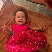 Avis joined the competition — help win amazing prizes! baby, child, red_dress, golden_hearts, blanket, smile, curly_hair, infant, lying_down, soft_lighting, indoors, cozy, happy, cute, portrait, toddler, fabric, texture, relaxed, person