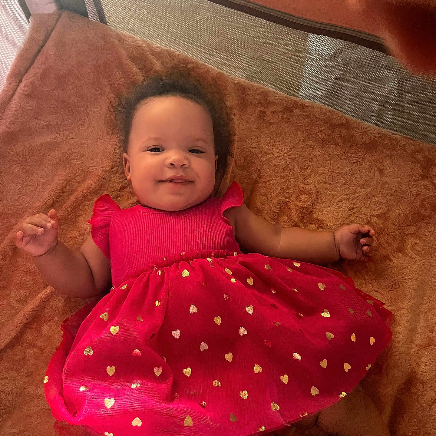 Avis joined the competition — help win amazing prizes! baby, child, red_dress, golden_hearts, blanket, smile, curly_hair, infant, lying_down, soft_lighting, indoors, cozy, happy, cute, portrait, toddler, fabric, texture, relaxed, person