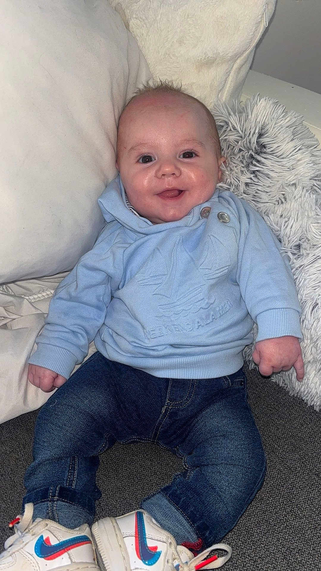 Isaac a rejoint le concours — aidez-le/la à gagner de superbes lots ! baby, child, smiling, blue_sweater, denim_jeans, white_shoes, nike, pillow, soft_texture, happy, indoor, casual_clothing, cute, infant, portrait, sitting, cozy, young_child, footwear, fashion