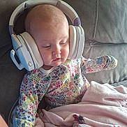 Aaliyah joined the competition — help win amazing prizes! baby, infant, child, sleeping, headphones, music, portrait, floral_clothing, onesie, blanket, pink_blanket, couch, indoor, seated, face, closed_eyes, cozy, colorful, home, photography
