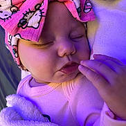 Nellia is registered to the contest to win money with this photo: baby, sleeping, blanket, headband, pink, cartoon, face, hand, cozy, soft, infant, child, cute, closeup, indoors, purple_light, apparel, toddler, peaceful, portrait