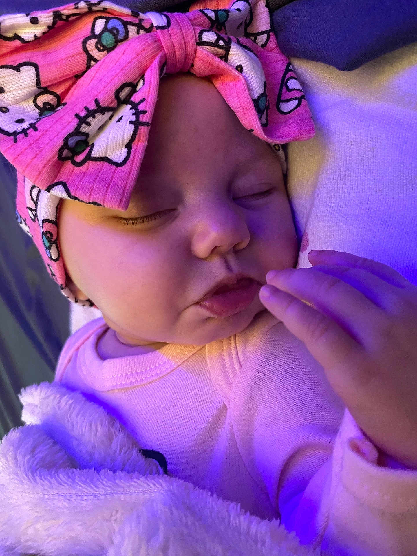 Nellia is registered to the contest to win money with this photo: baby, sleeping, blanket, headband, pink, cartoon, face, hand, cozy, soft, infant, child, cute, closeup, indoors, purple_light, apparel, toddler, peaceful, portrait