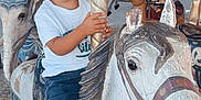 Malo a rejoint le concours — aidez-le/la à gagner de superbes lots ! child, toddler, boy, carousel, merry_go_round, painted_horse, amusement_ride, outdoor, trees, summer, blue_eyes, white_shoes, denim_pants, golden_pole, vintage, portrait, sitting, expression, playful, park