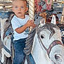 child, toddler, boy, carousel, merry_go_round, painted_horse, amusement_ride, outdoor, trees, summer, blue_eyes, white_shoes, denim_pants, golden_pole, vintage, portrait, sitting, expression, playful, park