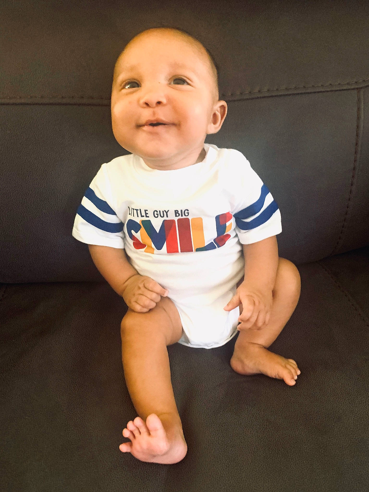 Huxley is registered to the contest to win money with this photo: arm, baby, baby_toddler_clothing, cheek, child, crawling, facial_expression, floor, fun, head, leg, person, product, sitting, skin, sleeve, smile, standing, t_shirt, toddler