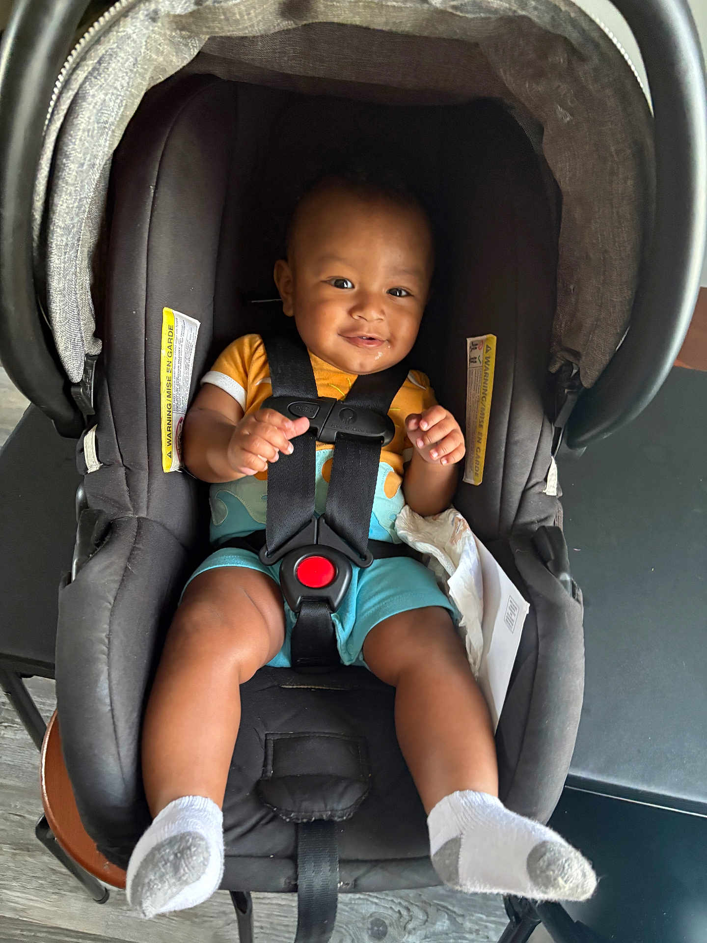 Amias is registered to the contest to win money with this photo: baby, car_seat, smiling, infant, child, socks, clothing, seatbelt, indoor, person, happy, face, head, sitting, black, orange, blue, drool, safety, cute