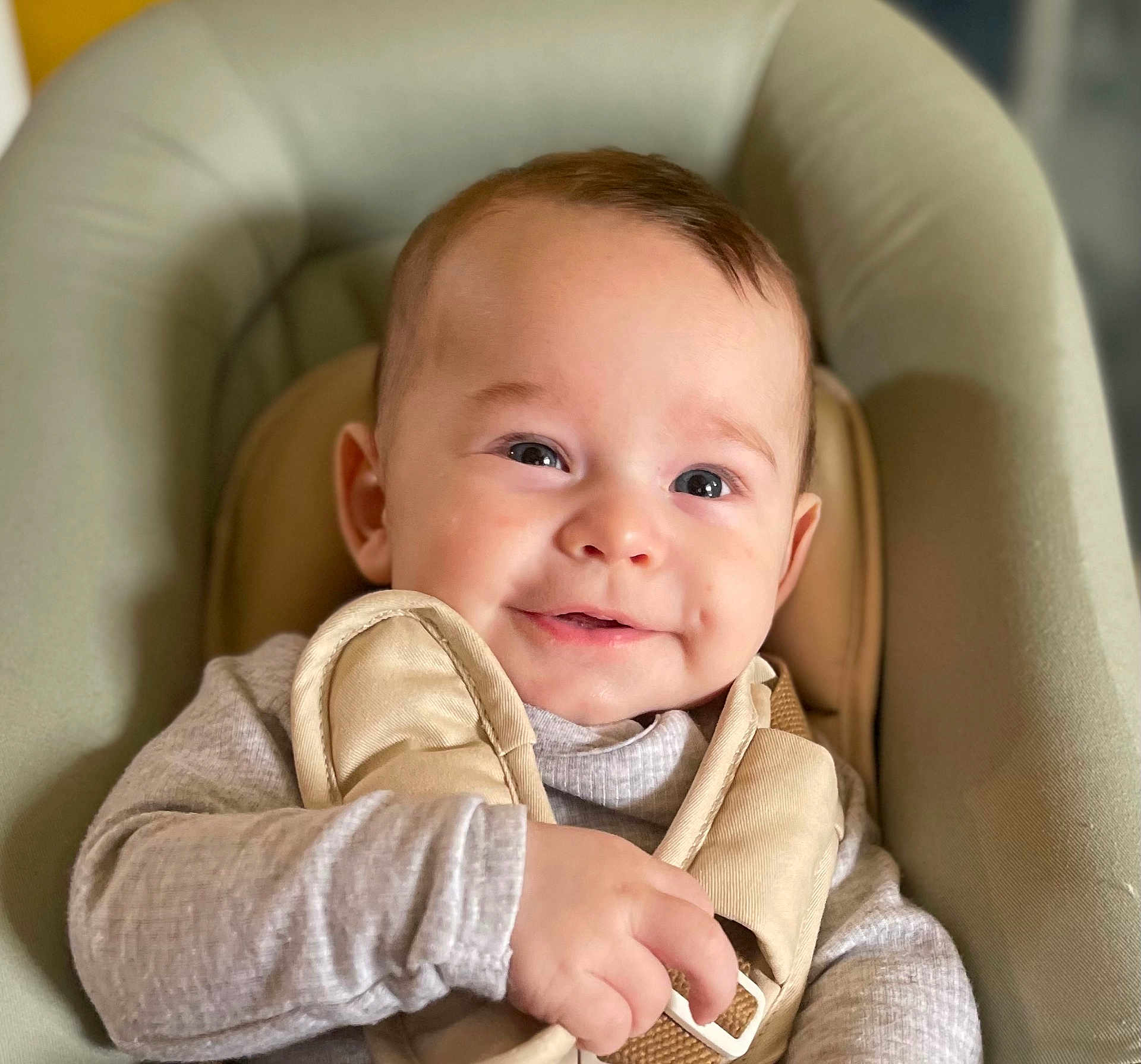 Jean-Antoine participe au concours pour gagner de l'argent avec cette photo : baby, infant, smiling, face, eyes, cheeks, dimples, hand, baby_seat, harness, clothing, onesie, beige, neutral_colors, closeup, portrait, indoor, soft_texture, cozy, seat_cushion