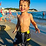 Ayden participe au concours pour gagner de l'argent avec cette photo : child, boy, beach, smiling, sand, water, sunlight, summer, swim_shorts, wet_hair, ocean, shore, playful, happy, outdoor, vacation, holiday, sunny, toddler, portrait