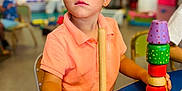 Ayden a rejoint le concours — aidez-le/la à gagner de superbes lots ! child, boy, toy, wooden_toy, stacking, classroom, education, table, colorful, polo_shirt, focus, play, learning, indoor, preschool, young_child, seat, hand, curious, background