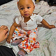 Honesty joined the competition — help win amazing prizes! baby, toddler, child, headband, earrings, white_top, floral_pants, sparkly_shoes, bed, bedding, blanket, indoors, portrait, sitting, cute, big_eyes, hand, skin, expression, bookshelf