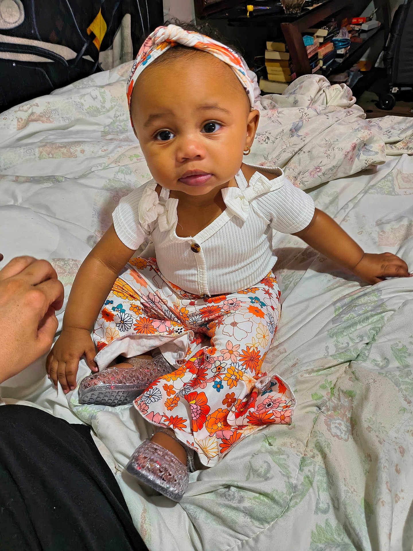 Honesty joined the competition — help win amazing prizes! baby, toddler, child, headband, earrings, white_top, floral_pants, sparkly_shoes, bed, bedding, blanket, indoors, portrait, sitting, cute, big_eyes, hand, skin, expression, bookshelf