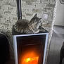 cat, stove, fire, indoor, warm, cozy, stone_wall, pet, animal, feline, relaxing, home, heating, fireplace, comfort, domestic, fur, resting, appliance, glow