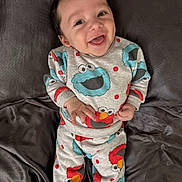 Roman joined the competition — help win amazing prizes! baby, child, smiling, pajamas, sesame_street, elmo, cookie_monster, lying_down, blanket, happy, cute, infant, clothing, portrait, indoors, face, person, toddler, cozy, colorful