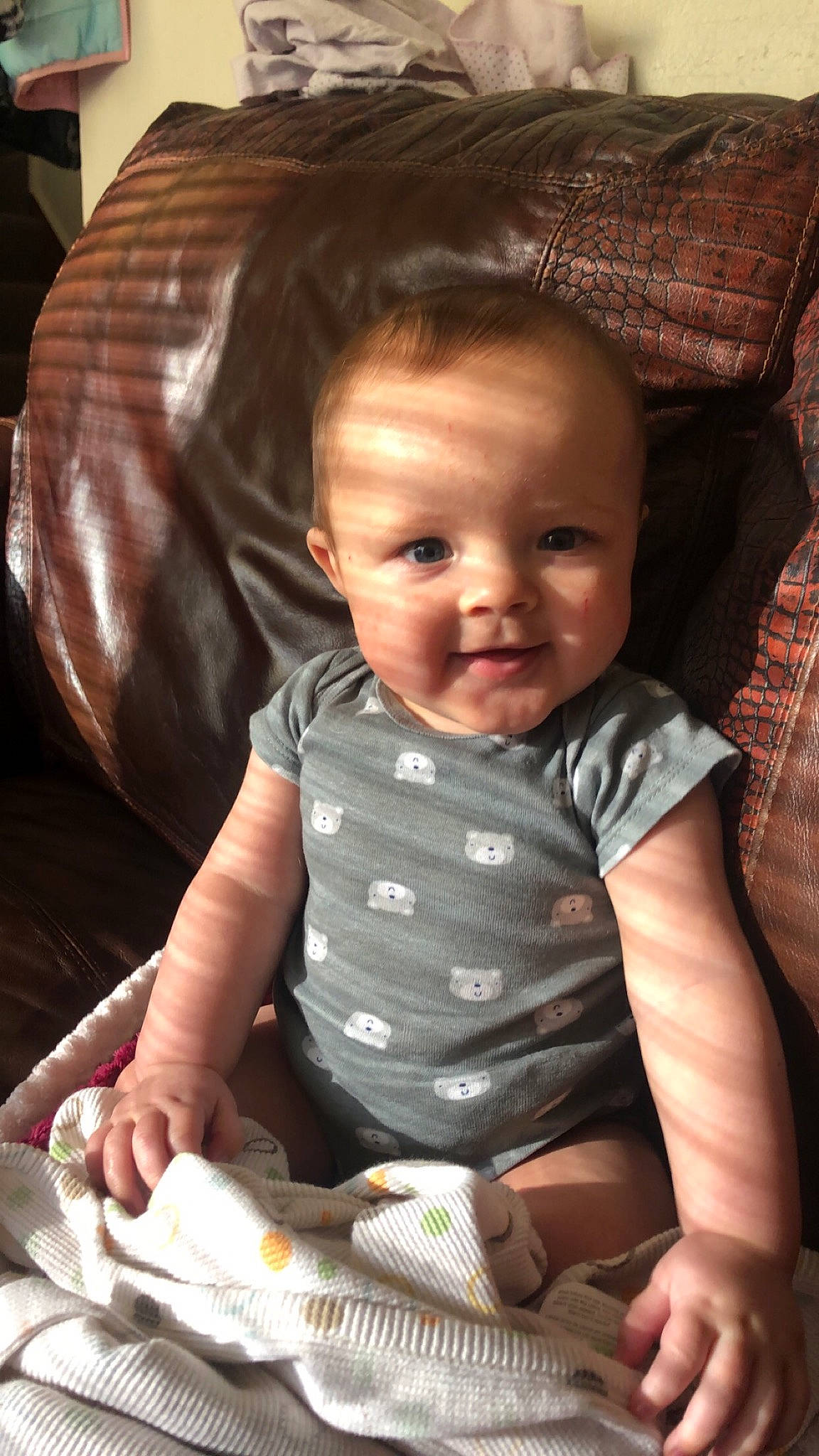 Davis is registered to the contest to win money with this photo: baby, baby_products, baby_toddler_clothing, cheek, child, comfort, couch, eye, finger, iris, lap, linens, living_room, mouth, nose, person, plaid, sitting, skin, toddler