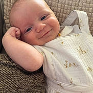 Léo a rejoint le concours — aidez-le/la à gagner de superbes lots ! baby, child, smile, face, arm, cushion, clothing, white_outfit, duck_prints, relaxed, portrait, indoors, close_up, skin, head, happy, infant, texture, person, cute