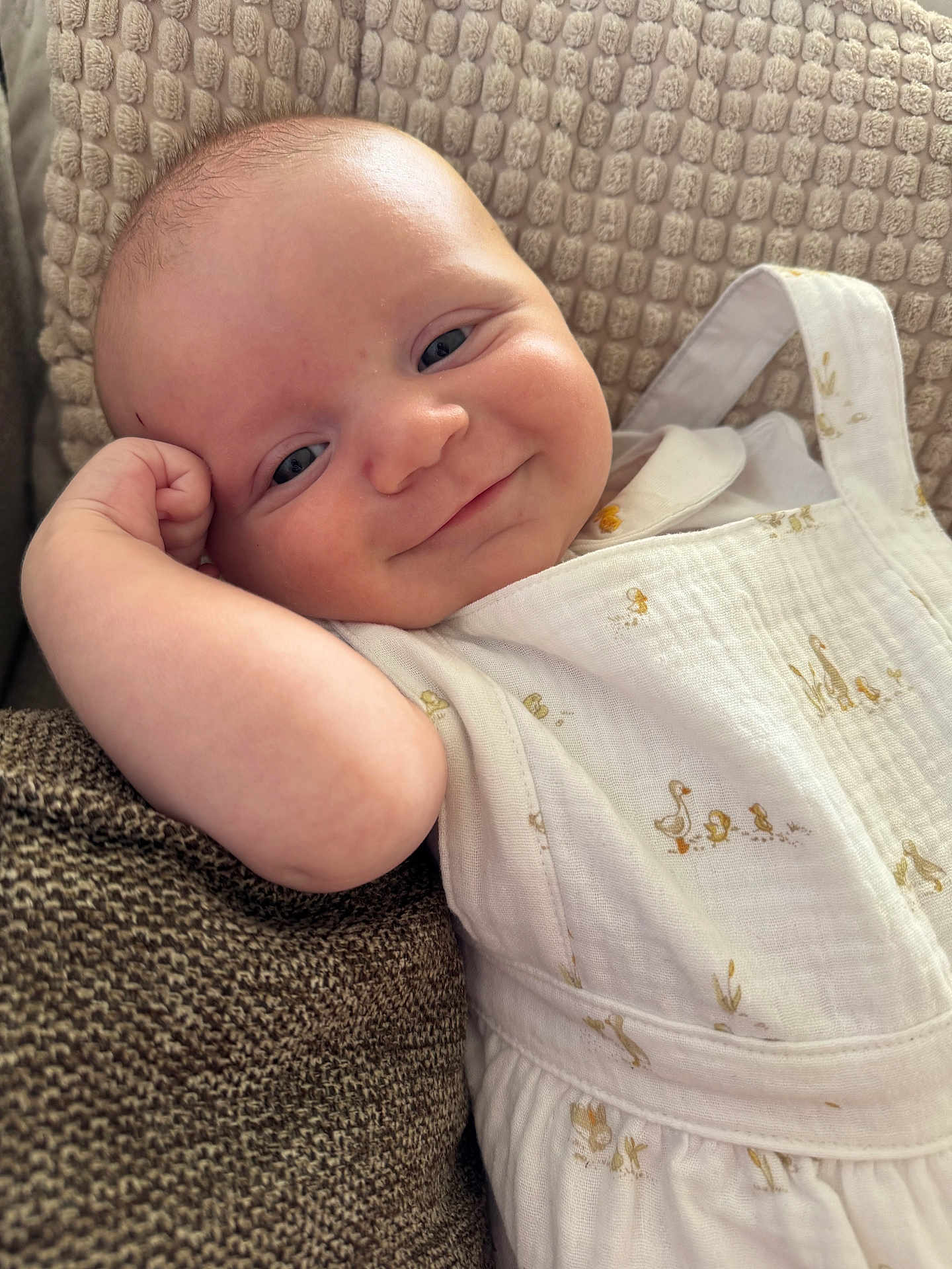 Léo a rejoint le concours — aidez-le/la à gagner de superbes lots ! baby, child, smile, face, arm, cushion, clothing, white_outfit, duck_prints, relaxed, portrait, indoors, close_up, skin, head, happy, infant, texture, person, cute