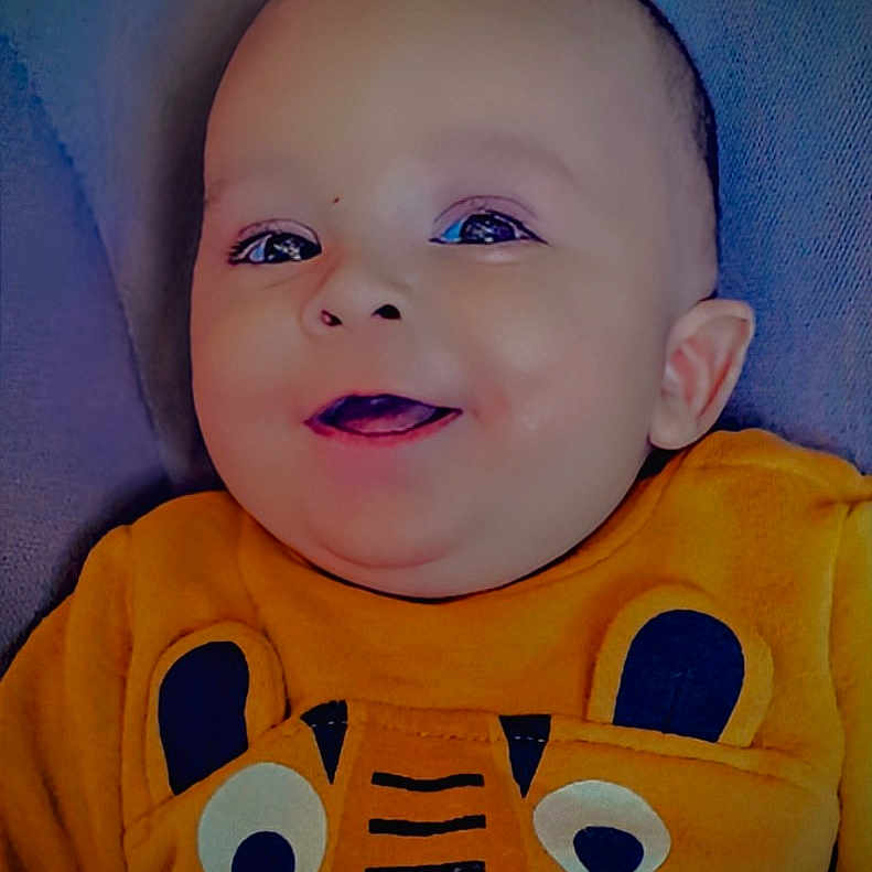 Elidjah participe au concours pour gagner de l'argent avec cette photo : apparel, baby, cheerful, child, closeup, cute, expression, face, happy, head, indoor, infant, orange_clothing, person, portrait, sitting, smile, soft_background, tiger_design, young