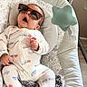 baby, sunglasses, infant, baby_seat, onesie, toy, star, mobile, cute, child, relaxed, indoors, sleepwear, patterned_clothing, small_hands, floor, plush, comfort, head_support, expression