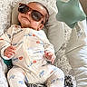 baby, sunglasses, onesie, baby_seat, toy, star_toy, infant, patterned_clothing, relaxed, cute, indoor, comfort, child, sleepy, head_support, baby_girl_or_boy, soft_toy, fashion, protective_eyewear, smile
