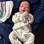 newborn, baby, infant, onesie, mittens, blanket, sleepy, lying_down, soft_fabric, plush, cozy, indoor, child, cute, face, person, clothing, resting, home, comfort