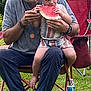 Tony joined the competition — help win amazing prizes! child, toddler, watermelon, eating, outdoor, grass, chair, adult, man, hat, glasses, casual_clothing, summer, nature, family, bonding, snack, barefoot, red_chair, water_bottle