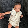Ahmyus is registered to the contest to win money with this photo: baby, child, infant, couch, sofa, hand, holding, striped_clothing, romper, socks, person, face, skin, furniture, indoors, seated, cute, young, expression, comfort