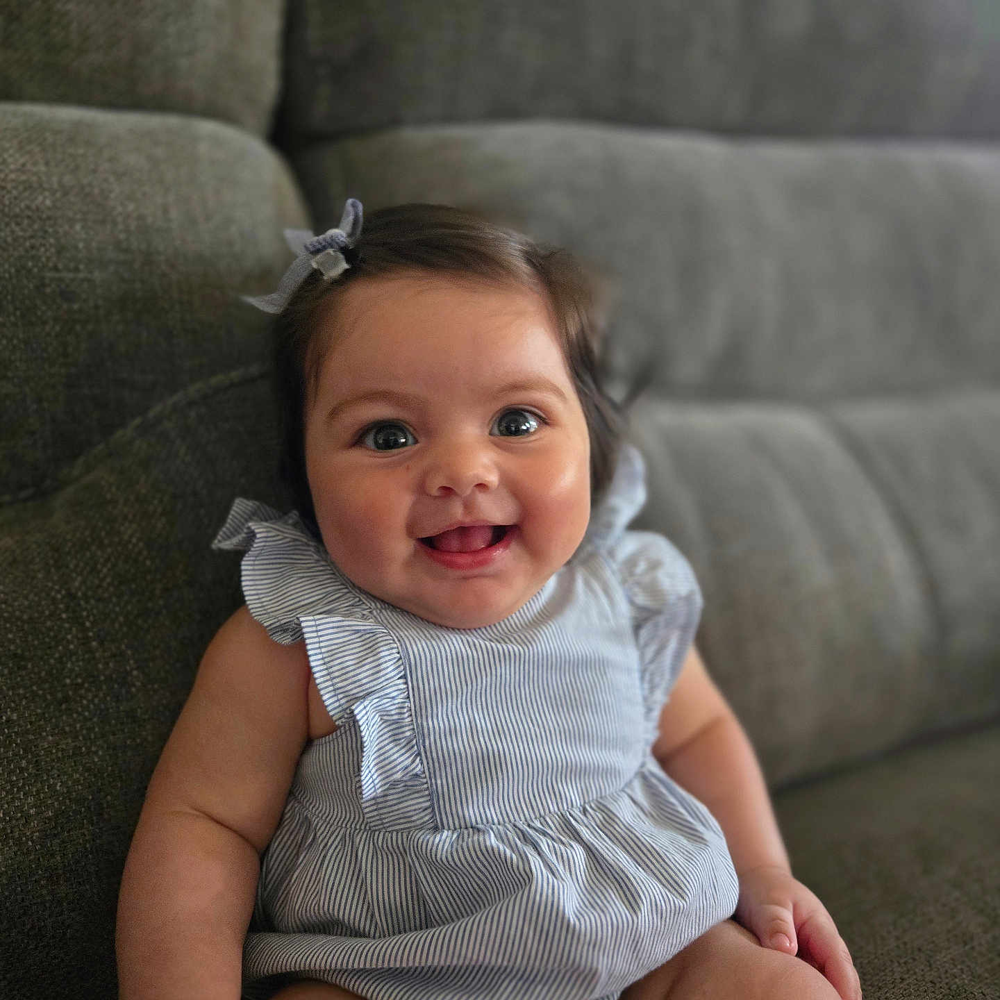 Mia is registered to the contest to win money with this photo: baby, smiling, child, cute, couch, indoor, portrait, happy, clothing, bow, striped, sitting, infant, furniture, person, skin, face, head, cheerful, young