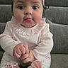 Mia joined the competition — help win amazing prizes! baby, infant, child, pink_headband, pink_clothing, sitting, couch, grey_couch, hands, curious_expression, closeup, indoors, face, portrait, cute, young_child, soft_lighting, headband, long_sleeves, floral_pants