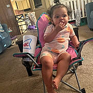 Riley joined the competition — help win amazing prizes! toddler, child, indoor, chair, pink, snack, curly_hair, living_room, carpet, crib, furniture, cup, casual_clothing, person, footwear_free, relaxed, home, baby, cute, seated