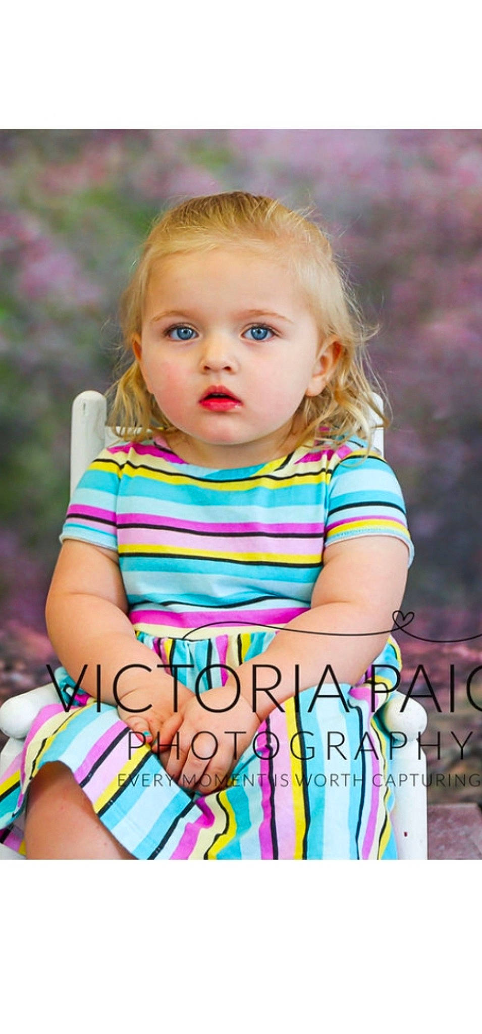Kennedy is registered to the contest to win money with this photo: baby_toddler_clothing, blond, child, face, fun, grass, hairstyle, happy, human_body, leisure, organ, outerwear, pattern, people_in_nature, person, pink, sitting, skin, sleeve, t_shirt