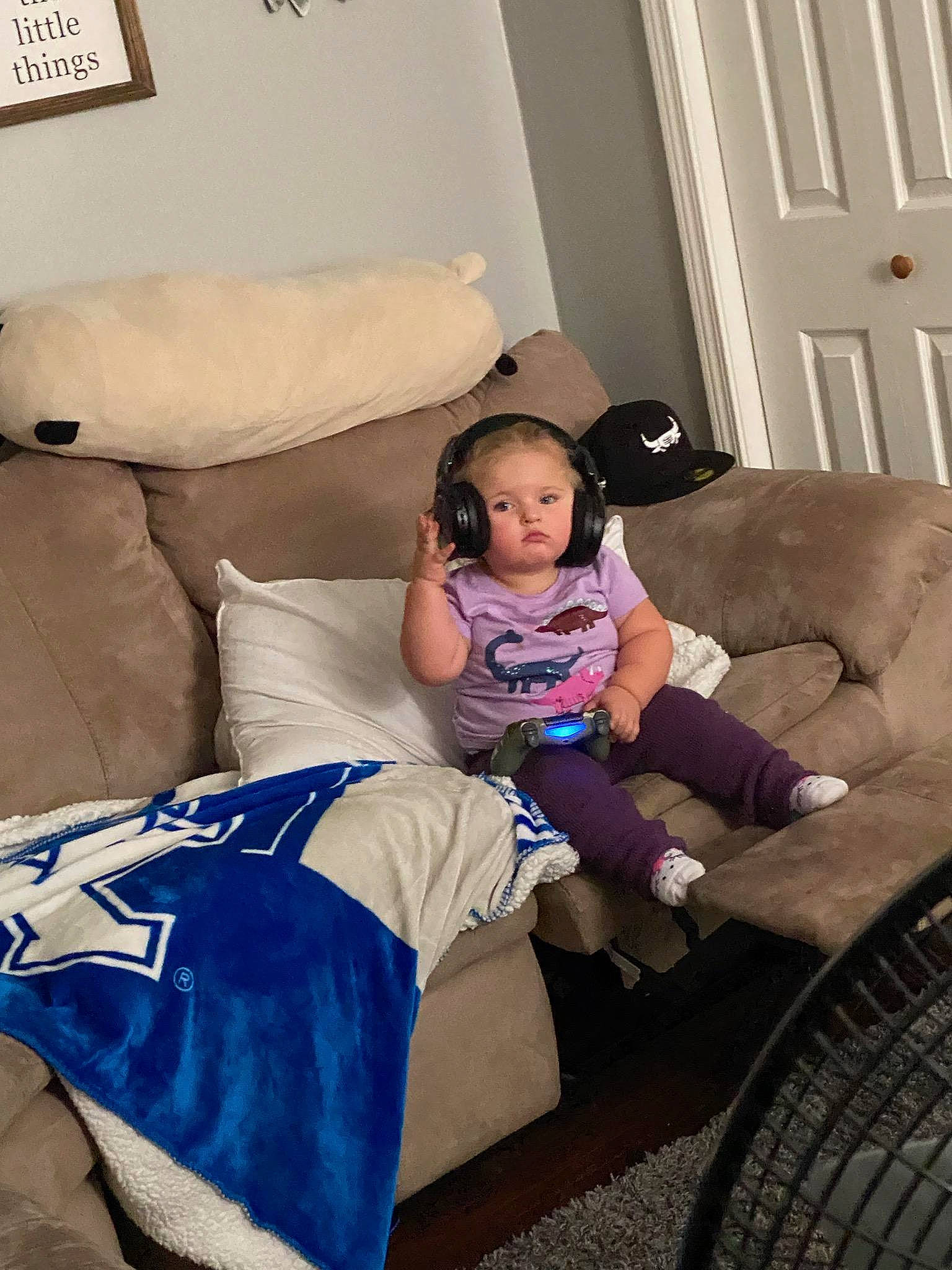 Kennedy is registered to the contest to win money with this photo: automotive_tire, beauty, child, comfort, couch, door, floor, flooring, furniture, human_leg, lap, leisure, living_room, mammal, person, pillow, sock, thigh, throw_pillow, toddler