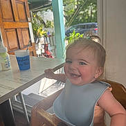 Marlow joined the competition — help win amazing prizes! baby, bib, bottle, child, cup, door, face, flag, greenery, hair, happy, high_chair, indoor, person, seat, smile, sunlight, table, window, wooden