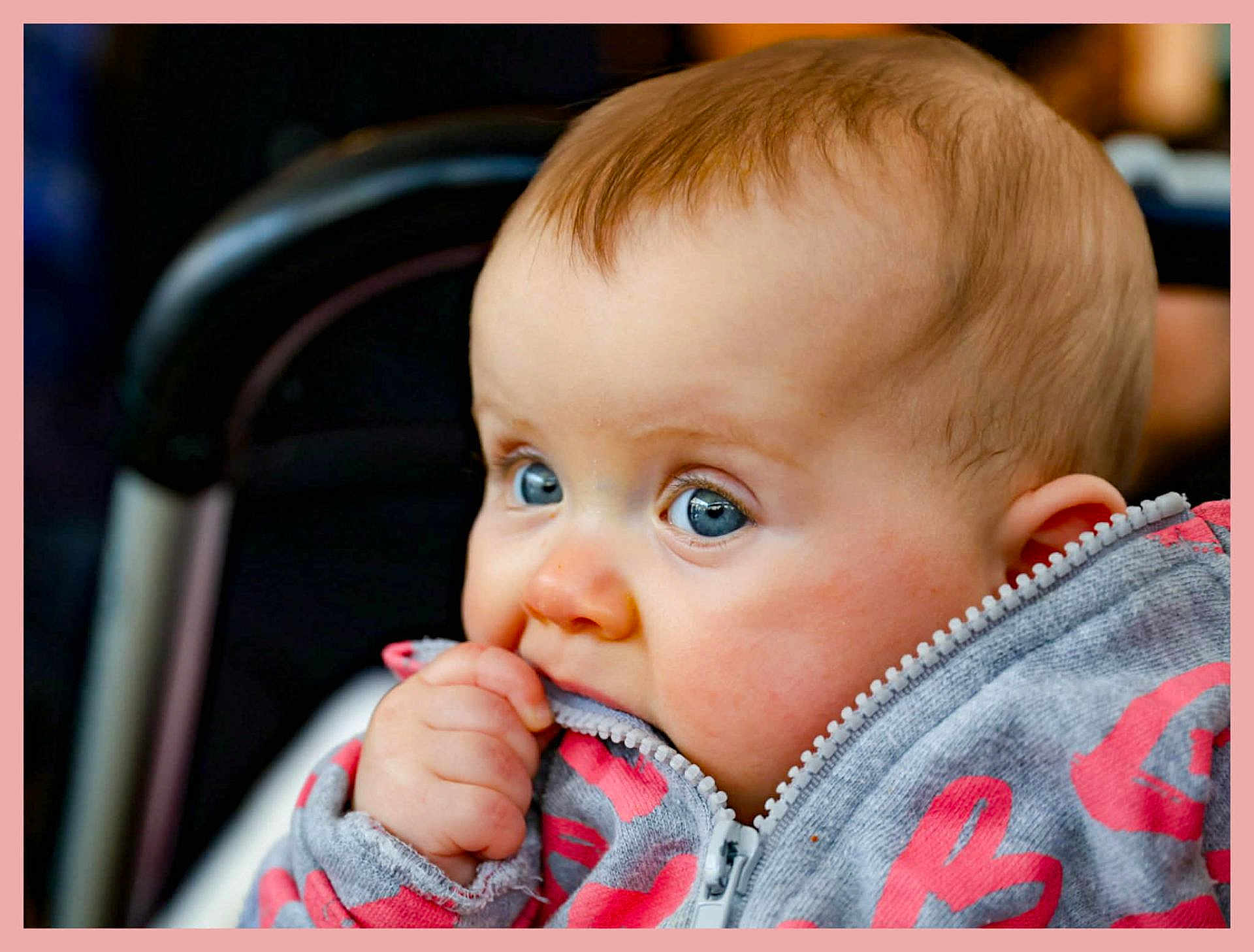 Rosalie a rejoint le concours — aidez-le/la à gagner de superbes lots ! baby, infant, child, toddler, face, blue_eyes, cheeks, hand, zipper, jacket, clothing, stroller, portrait, closeup, curious, teething, pink_border, candid, skin, eyelashes