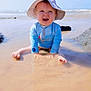 baby, child, beach, water, sun_hat, blue_sky, ocean, waves, sun_protection, happy, smiling, sitting, shallow_water, summer, outdoor, sand, sunny, playful, cute, vacation