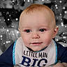 baby, child, bib, face, smile, sparkles, blue_clothing, closeup, infant, cute, portrait, hand, eyes, skin, head, sitting, young_child, expression, background_blur, indoor