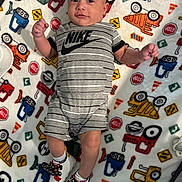 Thiago is registered to the contest to win money with this photo: baby, child, infant, blanket, clothing, nike, shoes, footwear, pattern, cartoon, vehicle, toy, fabric, cute, portrait, lying_down, indoor, colorful, person, socks